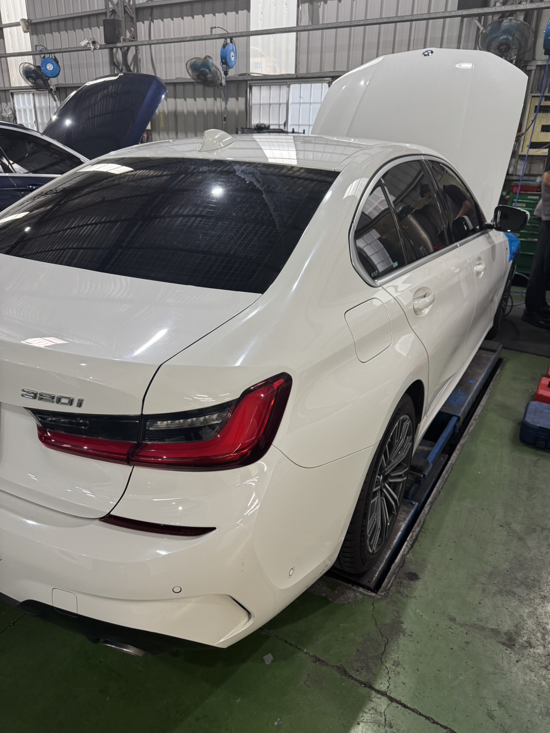 BMW 320i G20 白色入廠，車輛後 3/4 側面，引擎蓋開啟準備檢查