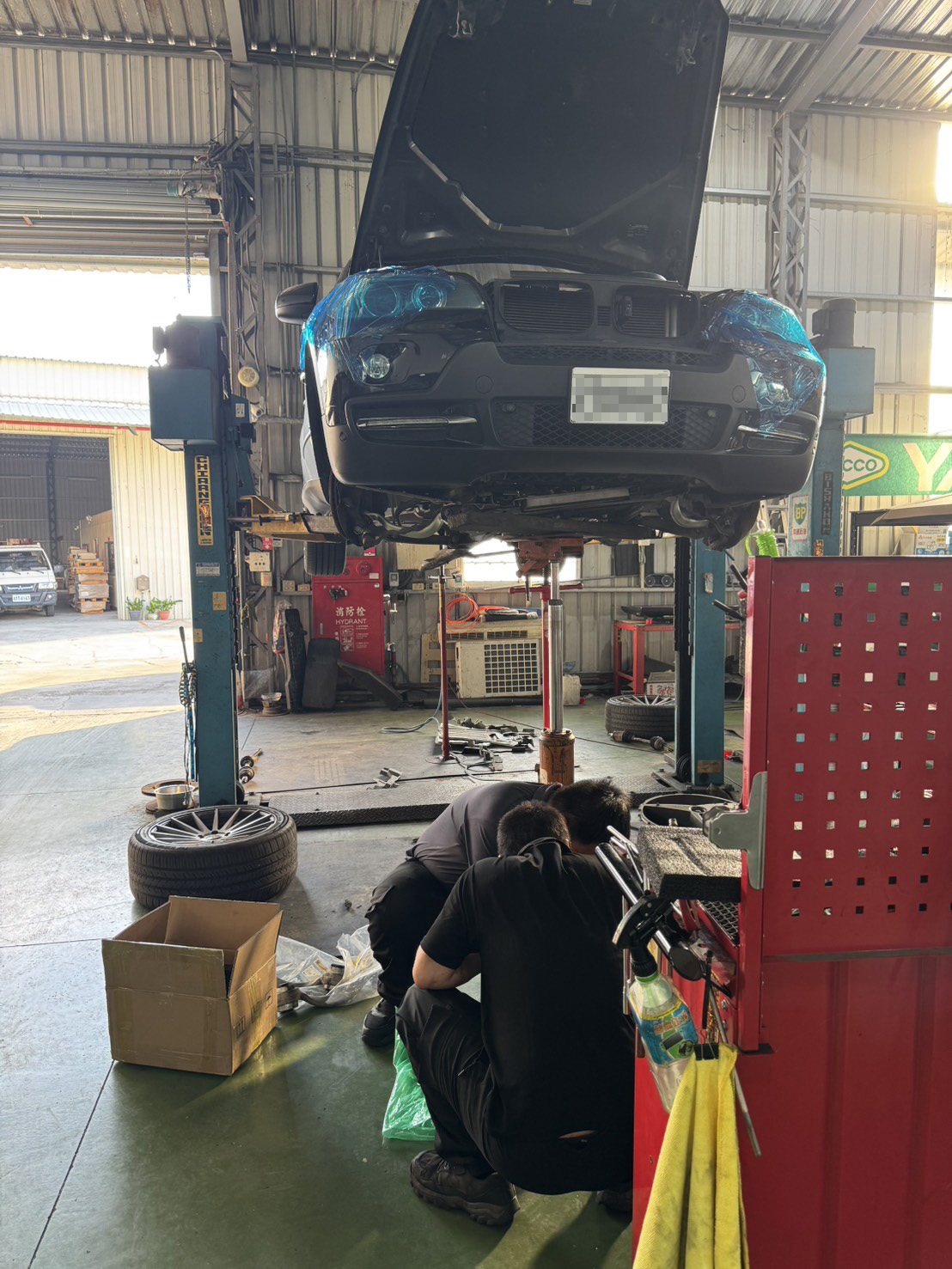技師在 BMW X5 E70 車底進行前差速器拆裝作業。